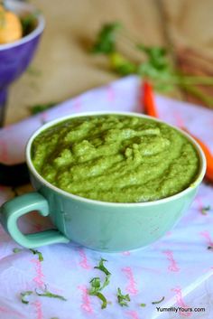 a bowl filled with green sauce next to carrots