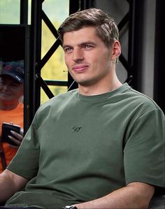 a man sitting in front of a window holding a cell phone