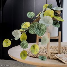 a wooden table topped with green and yellow paper leaves next to a potted plant