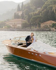 a bride and groom are kissing on the back of a boat in the water near some houses