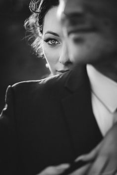 a black and white photo of a woman in a suit with her hand on her shoulder