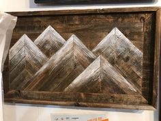 a wooden sign with mountains on it hanging from the side of a wall in a store