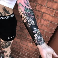 a woman's arm with flowers on it and a nike logo tattooed on the wrist