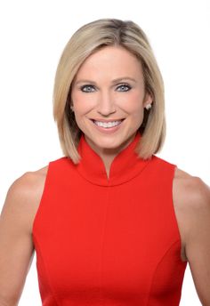 a woman in a red dress smiling at the camera with her hands on her hips