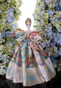 a barbie doll is standing in front of some blue and white flowers wearing a dress