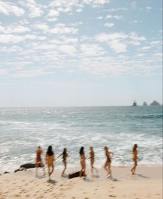 several people are walking on the beach with surfboards