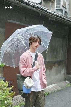 a young man holding an umbrella while walking down the street in the rain on a rainy day