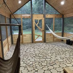 a hammock is in the middle of a room with wood walls and windows