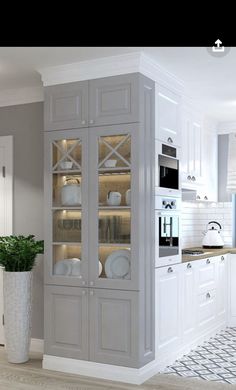 a kitchen with white cabinets and an oven in the corner, next to a potted plant