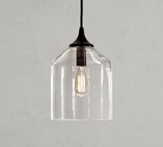 a clear glass pendant light hanging from a ceiling fixture with a black cord attached to it