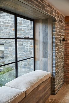 a brick wall and window in a room with two white pillows on the windowsill