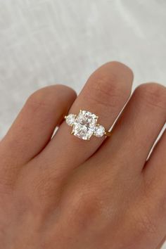 a woman's hand with a diamond ring on top of her finger and two diamonds in the middle