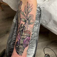 a person with a tattoo on their arm holding a cell phone and some plants in it