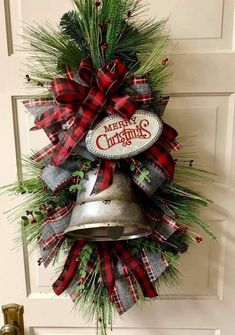 a christmas wreath with a bell hanging from the front door and evergreen leaves on it