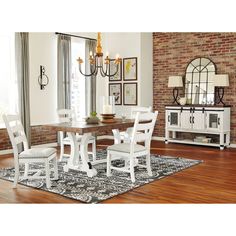 a dining room table with white chairs and a rug on the floor in front of it