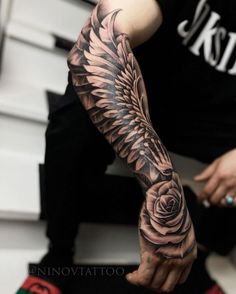 a person with a black and grey tattoo on their arm holding a rose in one hand