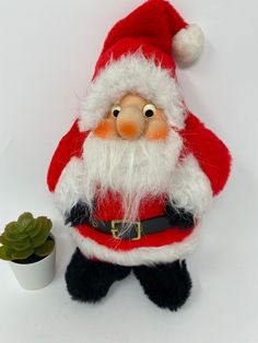 a santa clause doll next to a potted plant