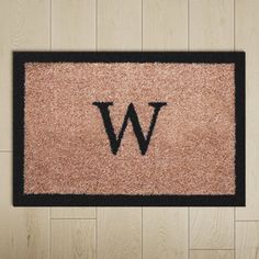 a door mat with the letter w on it in front of wood flooring area