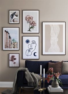 a living room with pictures on the wall and flowers in vases next to it