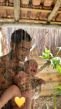 a man holding a baby in the rain with an orange heart on it's chest