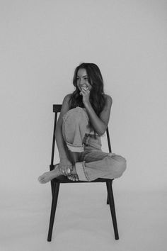 a black and white photo of a woman sitting in a chair with her hand on her mouth