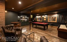 a game room with a pool table, couches and bar in the back ground