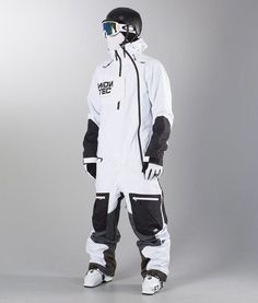 a snowboarder in white and black is posing for the camera on a gray background