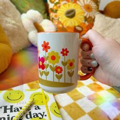 a person holding a coffee cup with flowers on it