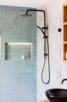 a bathroom with blue tiles and a black sink in the shower head is next to an open shelving unit