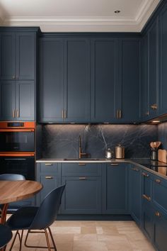 a kitchen with dark blue cabinets and marble counter tops, along with a wooden dining table