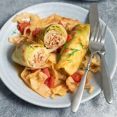 a white plate topped with pasta and artichokes next to a silver fork