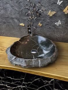 a bathroom sink sitting on top of a wooden counter next to a wall covered in butterflies