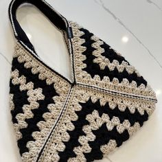 a crocheted black and white purse sitting on top of a marble countertop