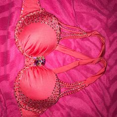 two pink bras laying on top of a pink bed covered in beads and sequins