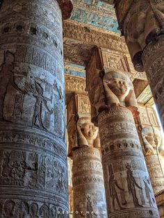 some very tall pillars with statues on them in the middle of an egyptian style building