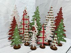 christmas trees are lined up on top of each other in front of a white wall