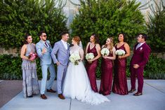 a group of people standing next to each other in front of some bushes and trees