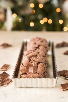 chocolate chip cookies in a pan on a counter next to a christmas tree with lights