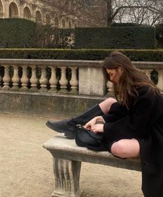 a woman sitting on top of a cement bench