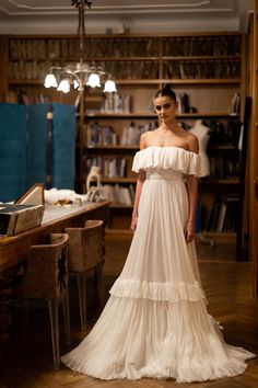 a woman in a white dress standing next to a table