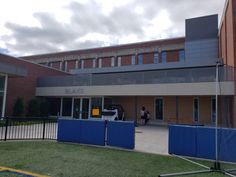 an outside view of a building with blue fencing around it and people standing in the doorway