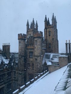 snow is falling on the roof of an old building with tall towers and spires