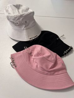 Pink black or white hat with safety pins and rings. Hella perfect for every day street wear!  Hats measure 23 inches and can be adjusted to be smaller, not bigger.  Note: please measure your head. I don't appreciate bad reviews from buyers who don't measure and who don't read the measurements.  Thank you in advance. Partnered design by Glitz & Candy Co.  Check them out on Facebook & Etsy! Drop-shipped by Glitz & Candy Co. Trendy Hats For Spring Music Festival, Edgy Adjustable Snapback Hat, Harajuku Style Adjustable Party Hat, Trendy Pink Hats For Music Festival, Trendy Bucket Hat For Music Festival, Trendy Black Hat For Music Festival, Trendy White Bucket Hat, Adjustable Summer Rave Hats, Trendy Adjustable Bucket Hat For Music Festival