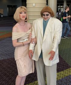 two people dressed in costumes standing next to each other on a carpeted flooring area