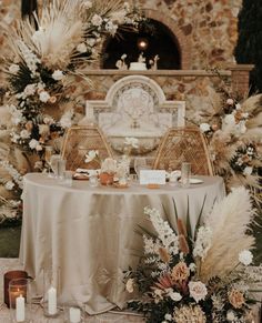 a table set up with flowers and candles in front of a stone wall at a wedding reception