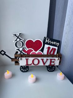 a wagon filled with candles and valentine's day cards on top of a table