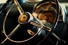 the steering wheel and dashboard of an old car with gold spokes on it's dash board