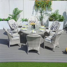 an outdoor table and chairs on a deck with flowers in vases next to it