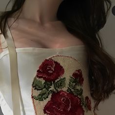 a close up of a woman's shoulder wearing a white top with red roses on it