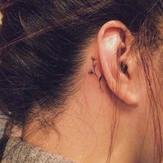 a woman's behind the ear tattoo with flowers on her left side and an arrow in the middle